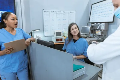 Group of nurses and a doctor collaborating at a hospital reception area with medical equipment in view.