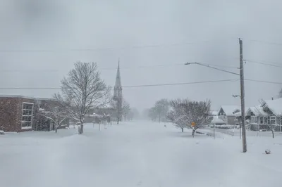 A serene winter scene of a snow-blanketed street in Wabasha, Minnesota with a church spire in the background.
