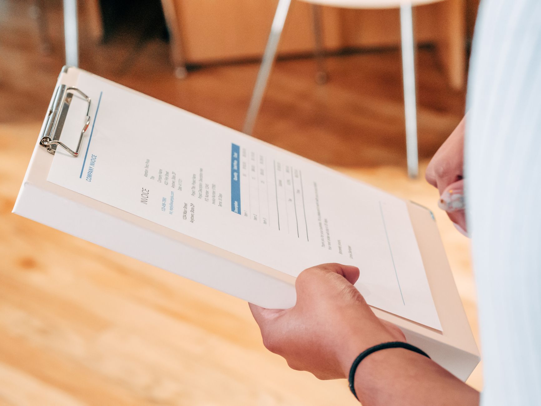 Close-up of hands holding a clipboard with business documents, indicating analysis and planning.